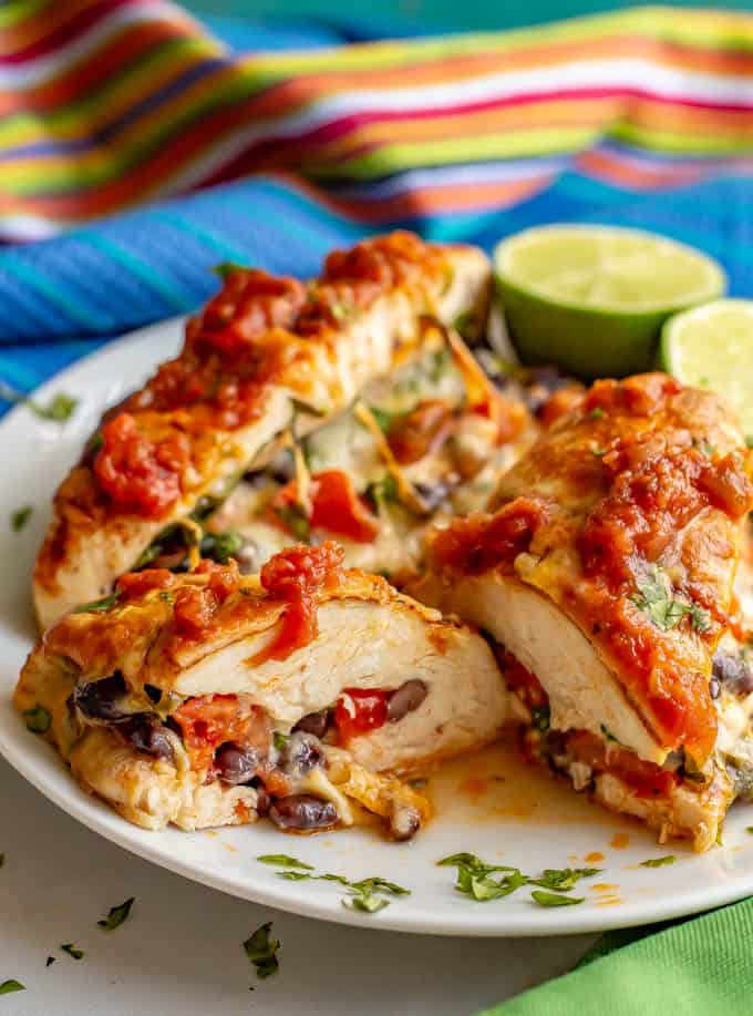 Stuffed Mexican chicken breasts with black beans, tomatoes and cheese served on a white plate