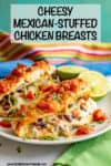 Two cheesy Mexican stuffed chicken breasts on a white plate with salsa on top and lime halves to the side.