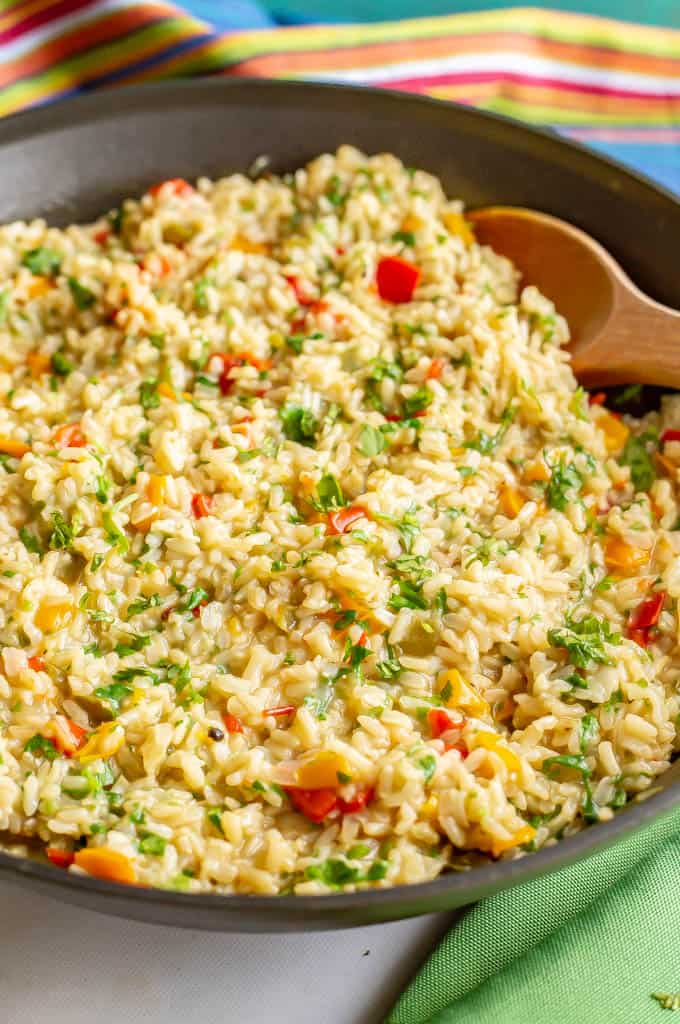 A skillet full of cooked brown rice and colorful bell peppers