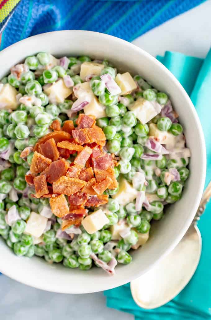 Classic pea salad with bacon and cheddar cheese in a white serving bowl