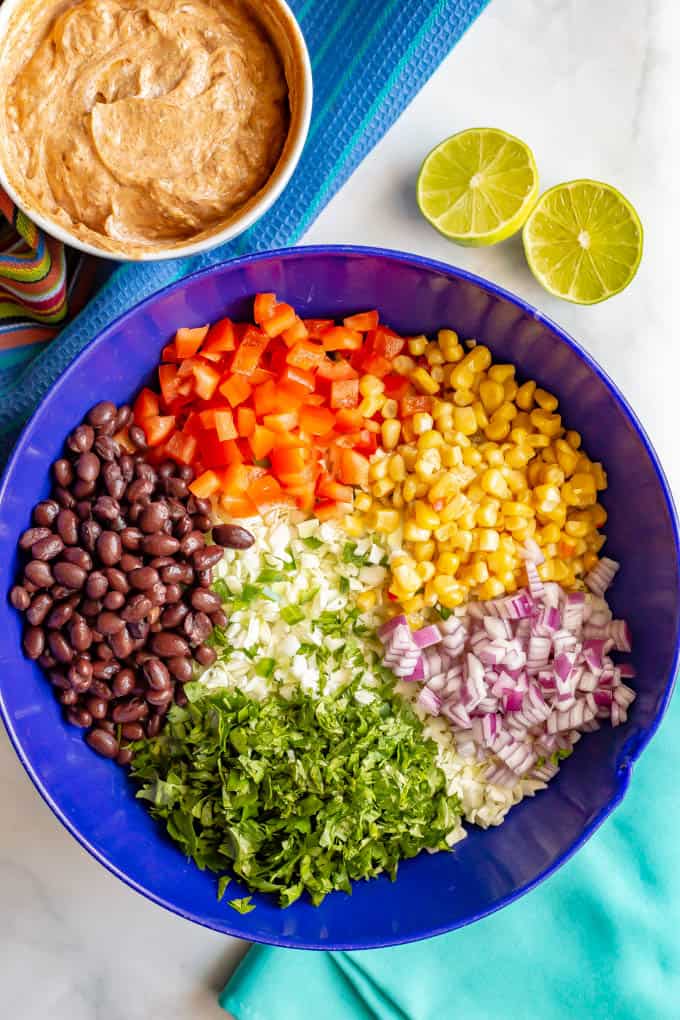 Ingredients to make creamy Mexican style coleslaw recipe arranged in a large blue bowl with taco dressing in a separate bowl