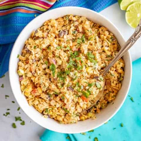 Loaded creamy coleslaw with black beans, peppers, corn and taco seasoning in a large white bowl
