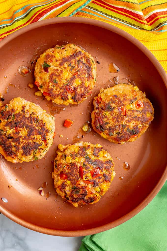 Southwest salmon patties cooking in a large skillet