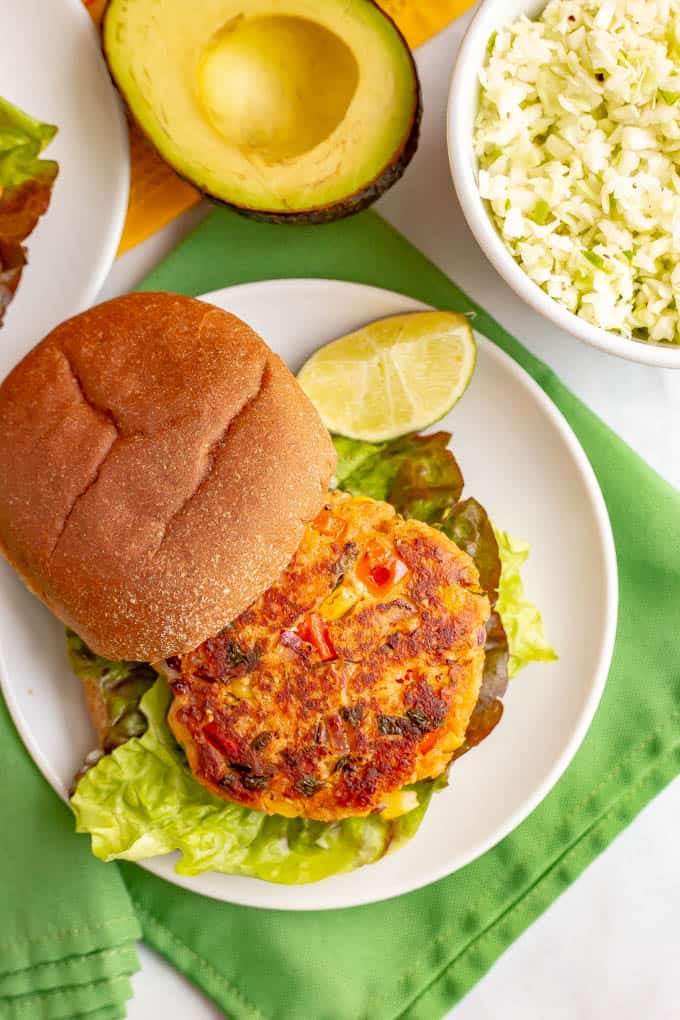 A homemade southwest style salmon burger on a bun on a white plate.