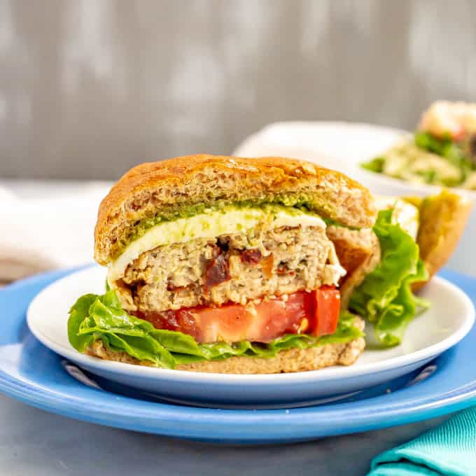 An Italian chicken burger cut in half to show the layers of the burger and sun-dried tomatoes in the burger patty