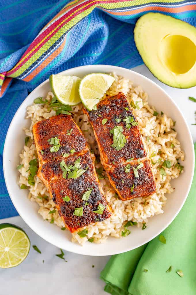 Baked salmon filets over a bed of rice in a white bowl with chopped cilantro