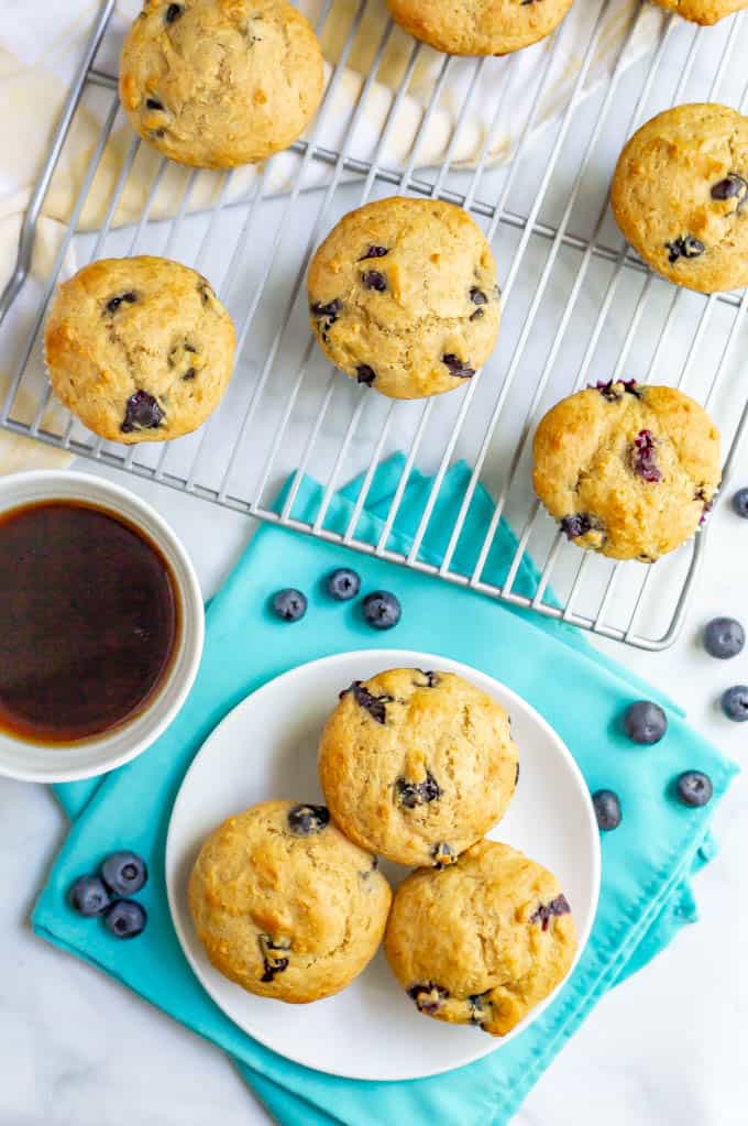 Blueberry muffins cooling on a wire rack and three served on a white plate