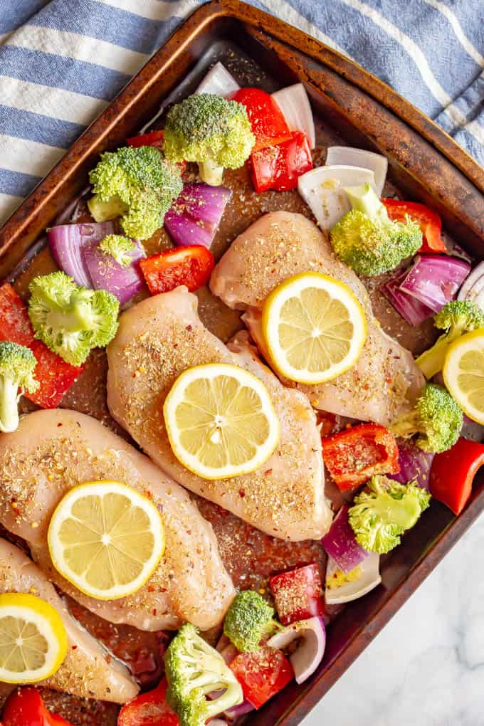 Raw chicken and vegetables arranged on a baking sheet