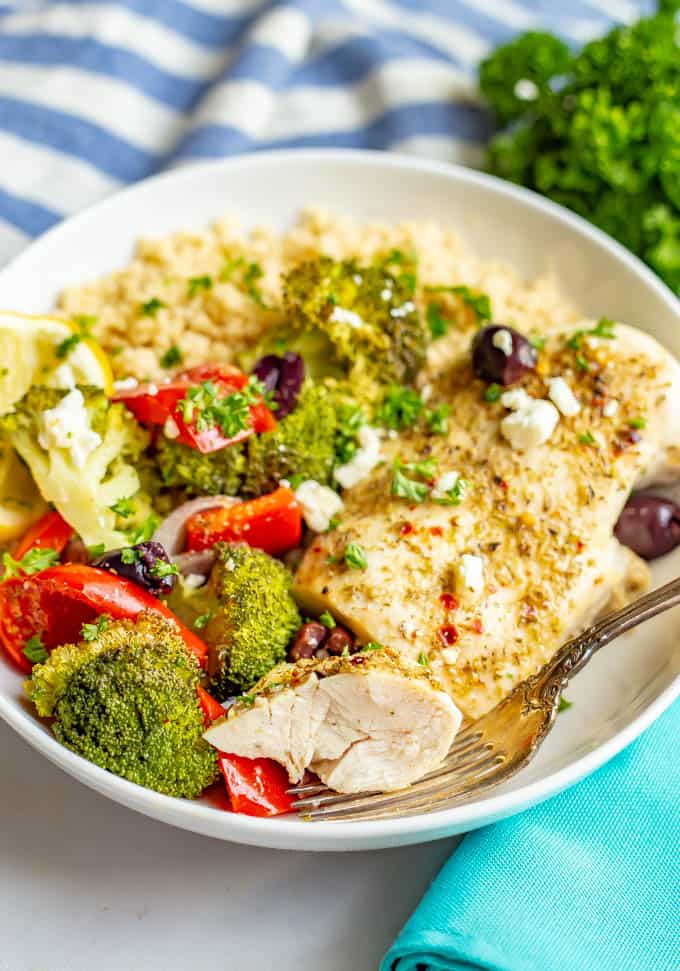 Close up of seasoned baked chicken and vegetables with rice in a white bowl