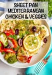 A low white bowl with couscous topped with roasted veggies and a chicken breast topped with a lemon slice.