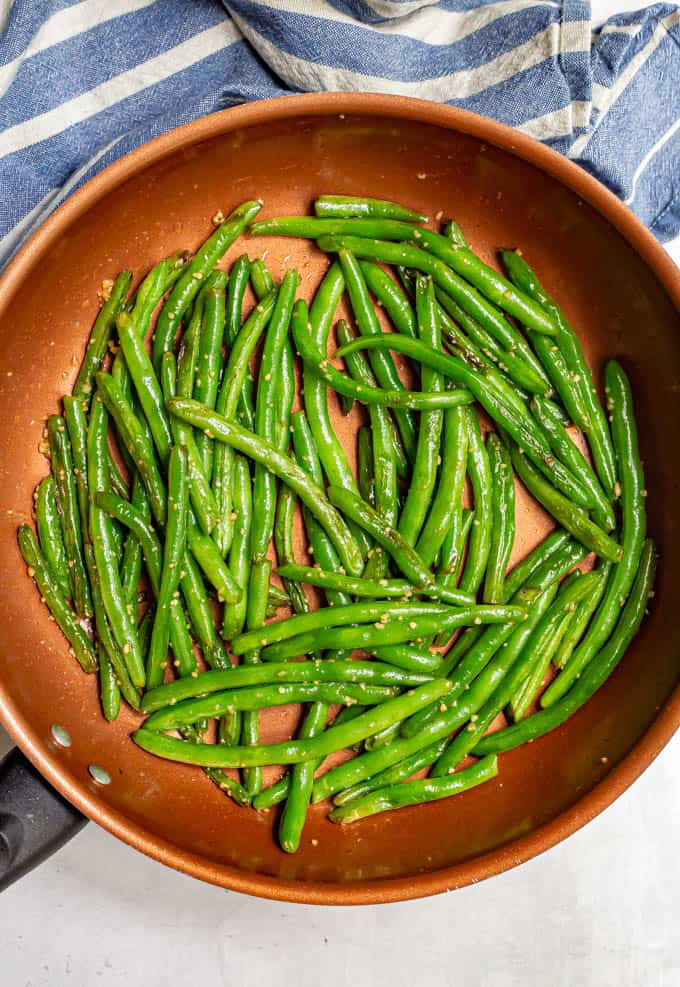 Green beans sautéed in butter in a large copper pan