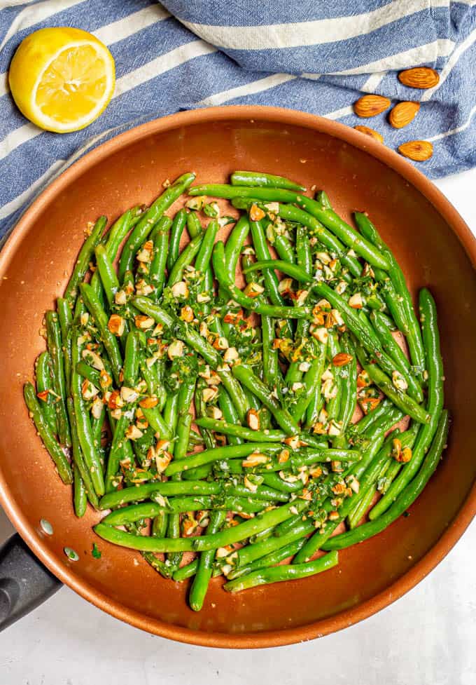 Green beans in a large copper pot after cooking and served with an almondine mixture on top