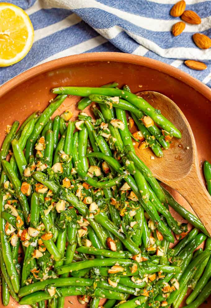 Green beans almondine being finished in a large copper skillet