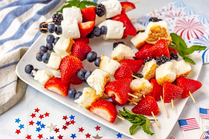 Strawberry, blueberry and angel food cake fruit kabobs on a plate with July 4th decorations