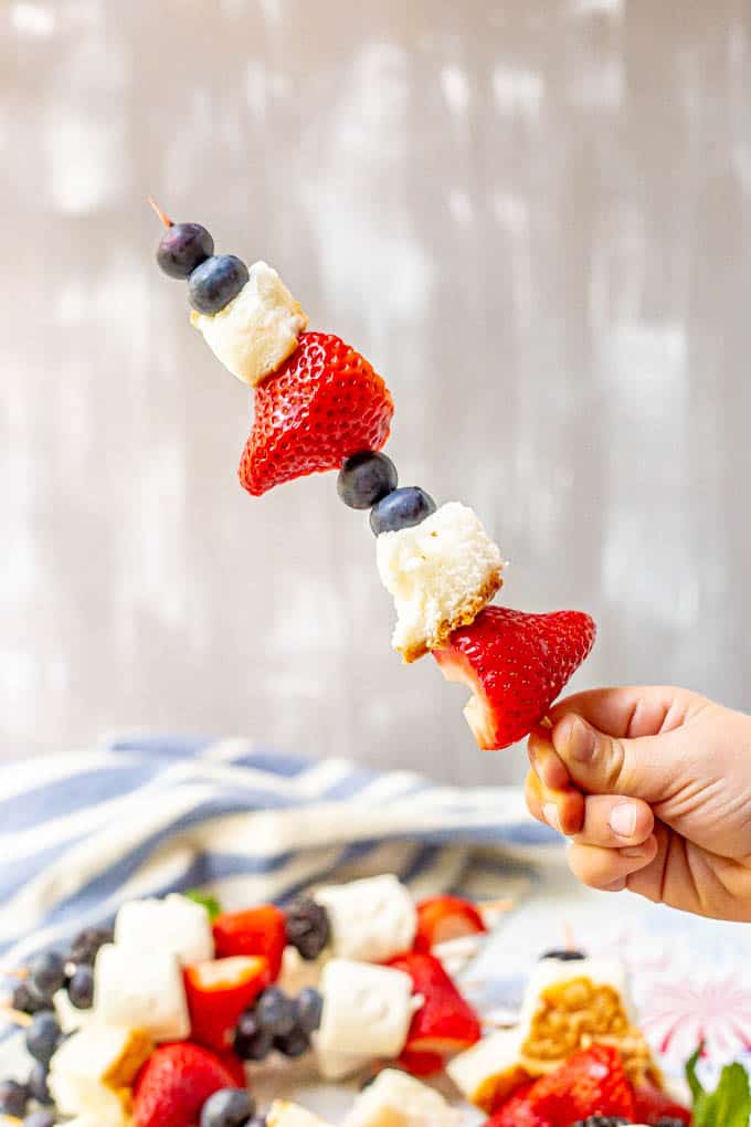 Fruit kabob being held with red white and blue fruits