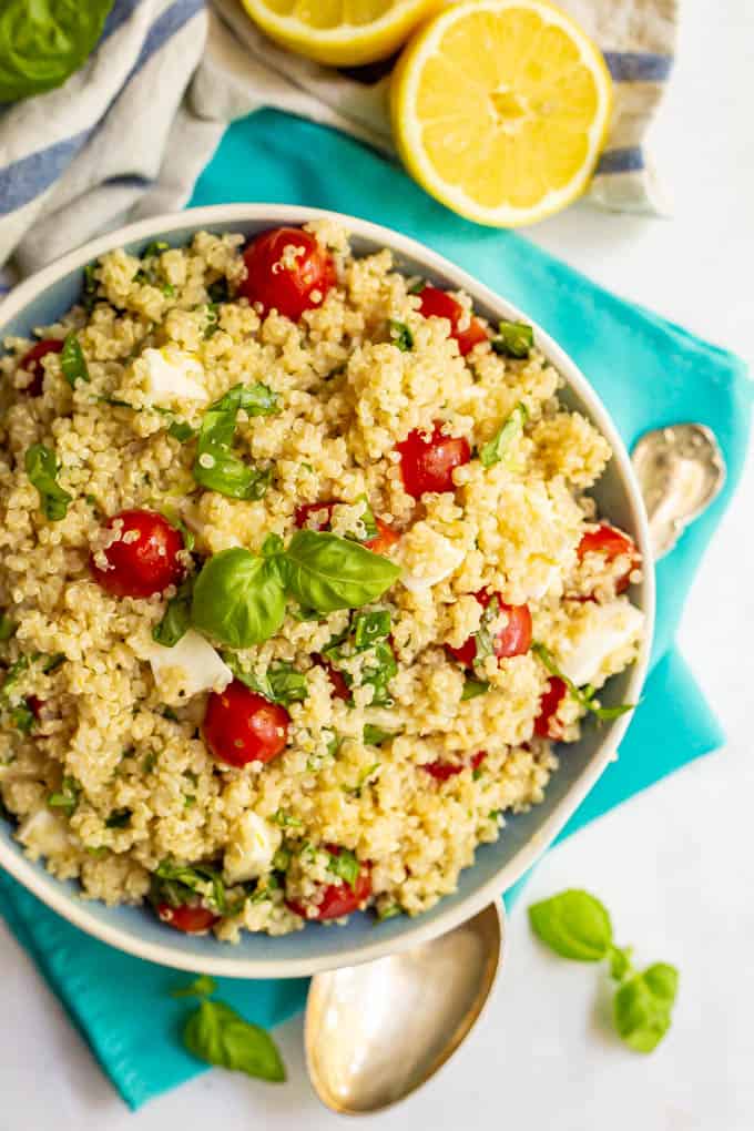 Caprese salad with quinoa and lemony vinaigrette with basil and lemons scattered nearby