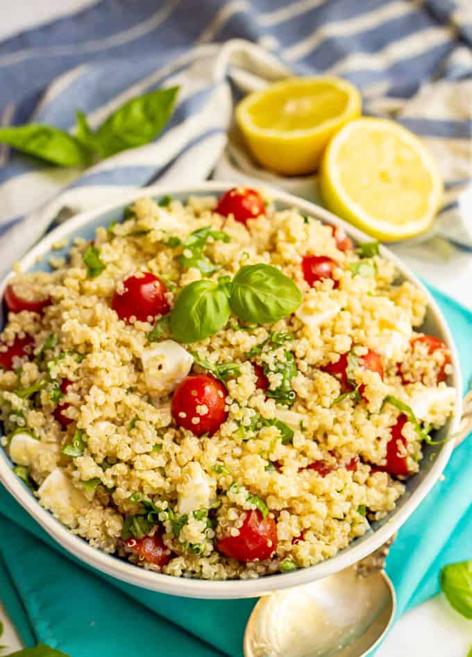 Salad of quinoa, tomatoes, mozzarella and basil with lemon vinaigrette and fresh lemons in the background