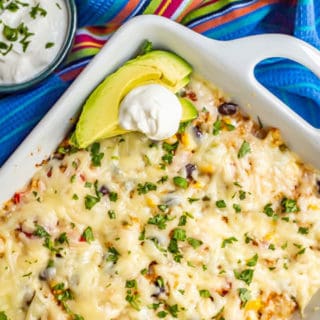 Mexican quinoa casserole baked in a baking dish with avocado and sour cream on top