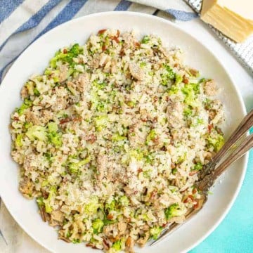 Bowl of wild rice with turkey sausage and broccoli all mixed together and two forks alongside