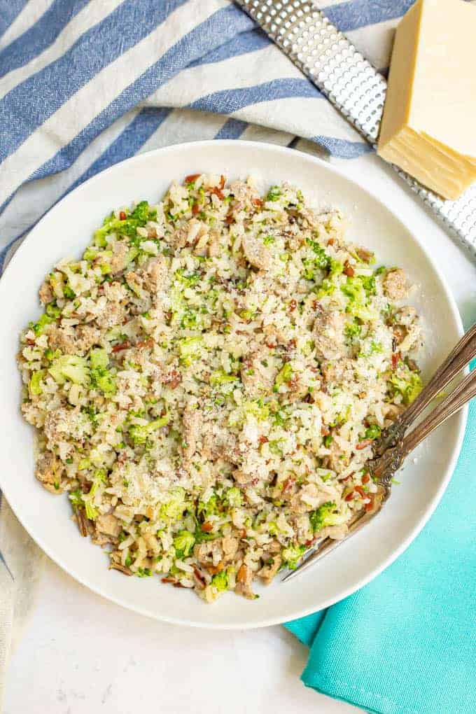 Bowl of wild rice with turkey sausage and broccoli all mixed together and two forks alongside