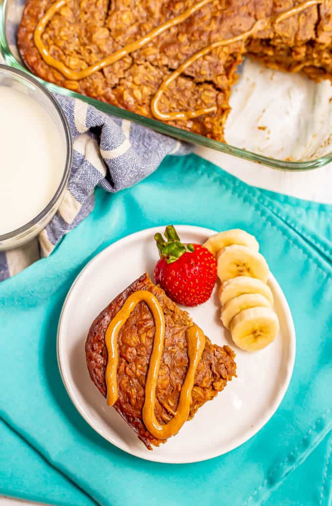 Baked oatmeal with peanut butter on top served on a white plate with fresh fruit