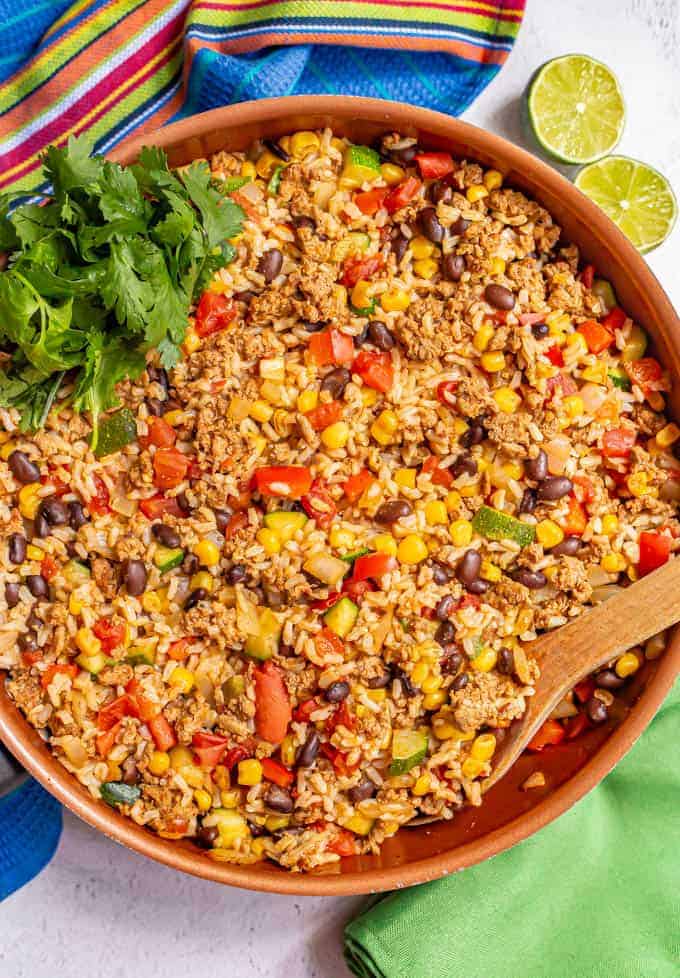 Large skillet with cooked ground turkey, brown rice, black beans and veggies and cilantro for garnish