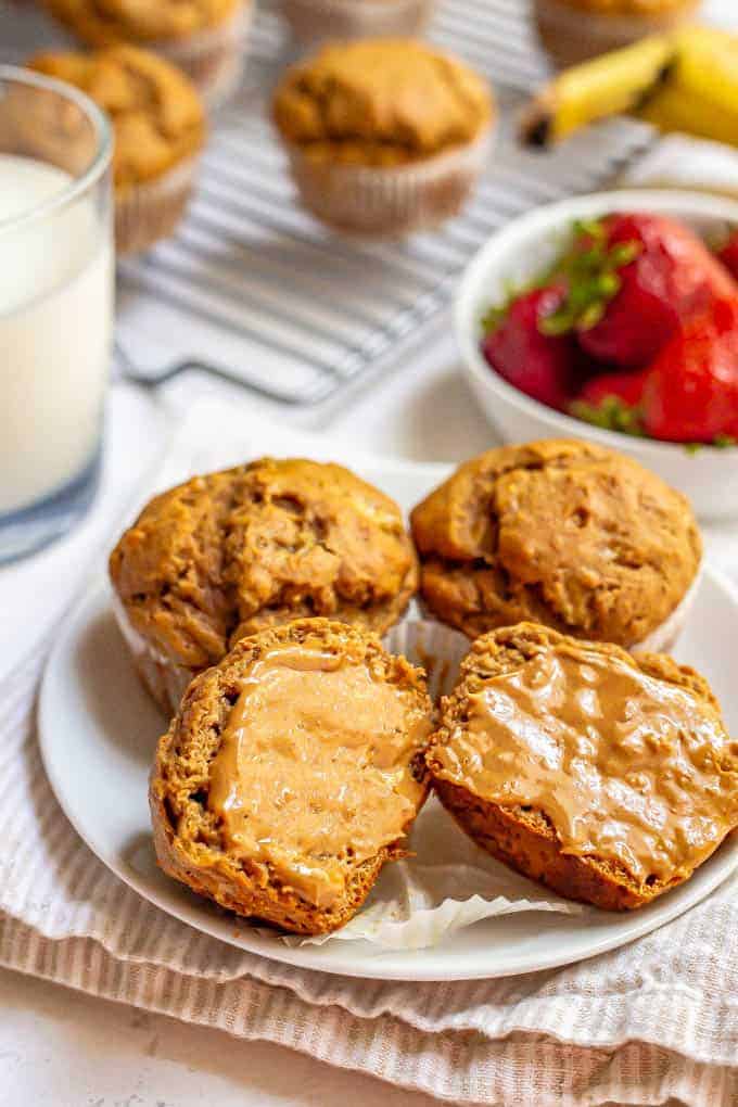 Muffins on a plate with one cut in half and smeared with peanut butter