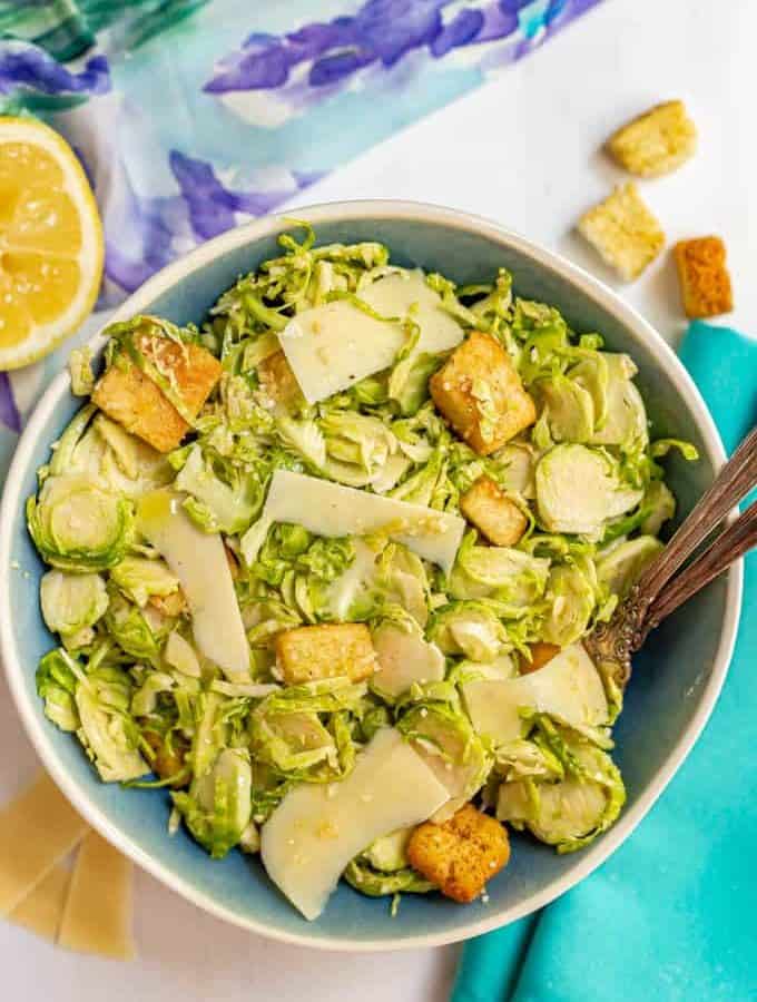 Brussel sprout Caesar salad served with two forks in a large blue and white bowl
