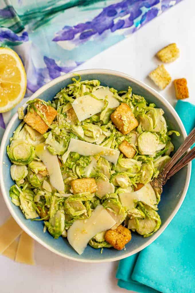 Brussel sprout Caesar salad served with two forks in a large blue and white bowl