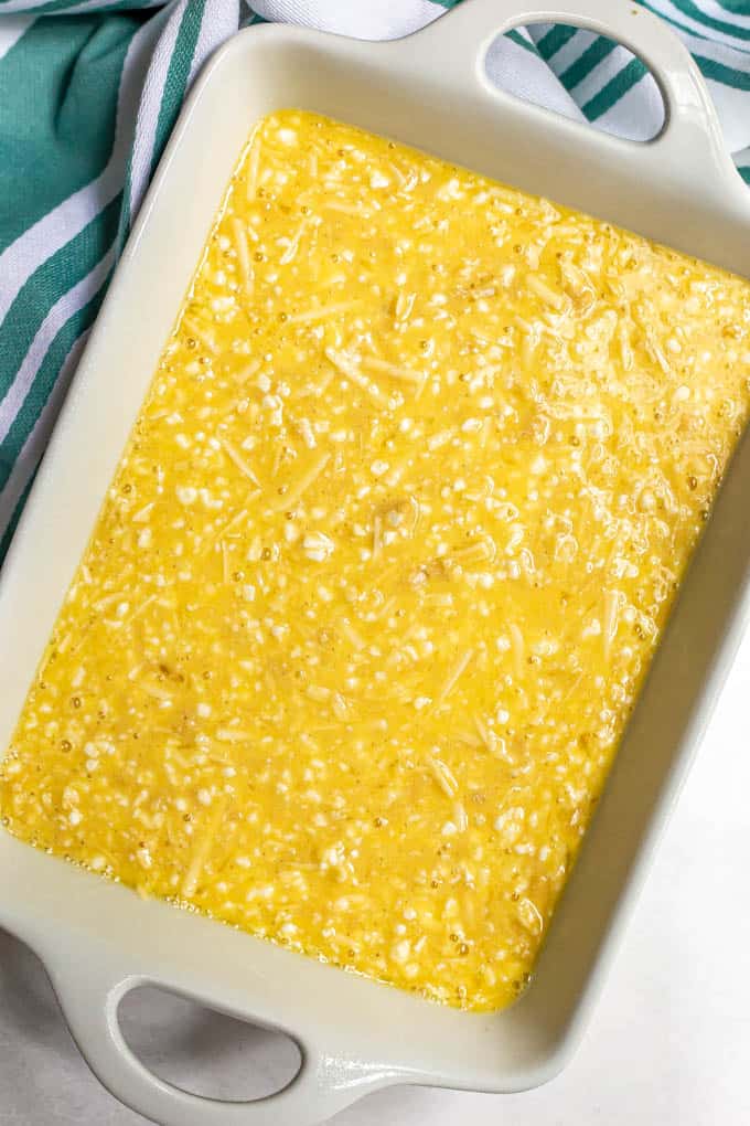 Eggs and cheese mixture in a white casserole dish before baking