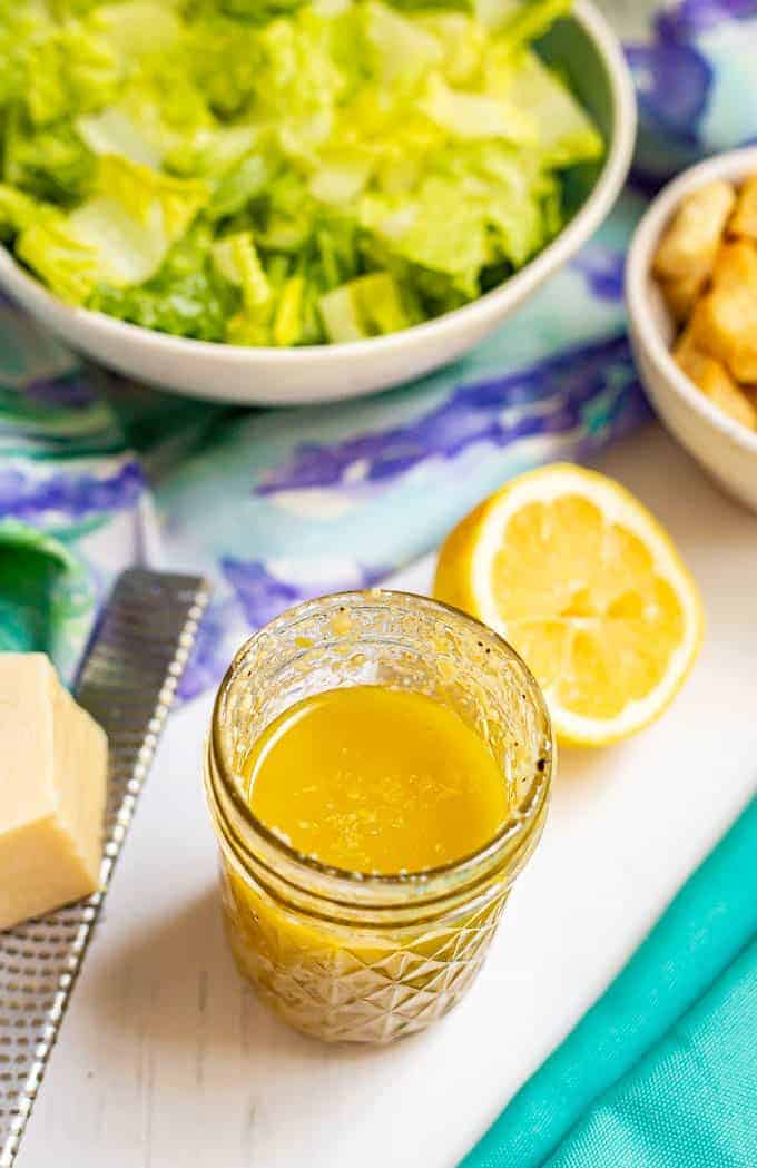 Creamy homemade salad dressing in a glass jar with salad fixings in the background