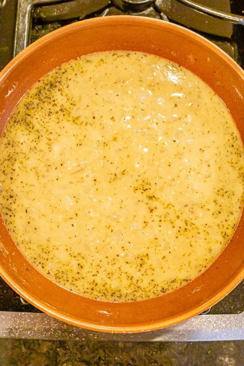 Broth mixture with onions and spices in a large pan on the stove