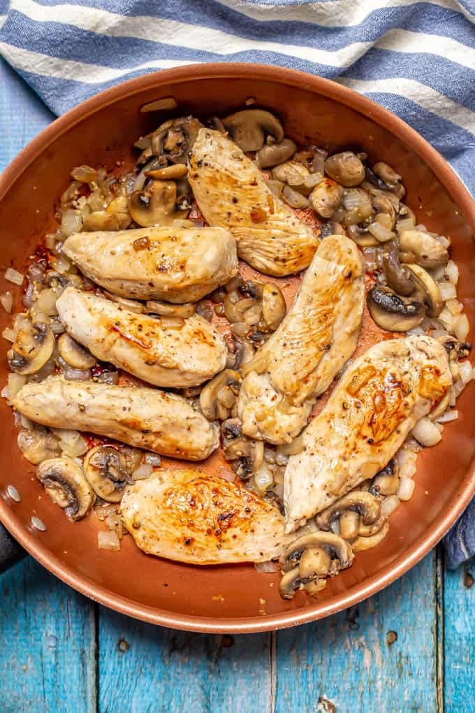 Sautéed onion, mushrooms and chicken strips in a large copper skillet