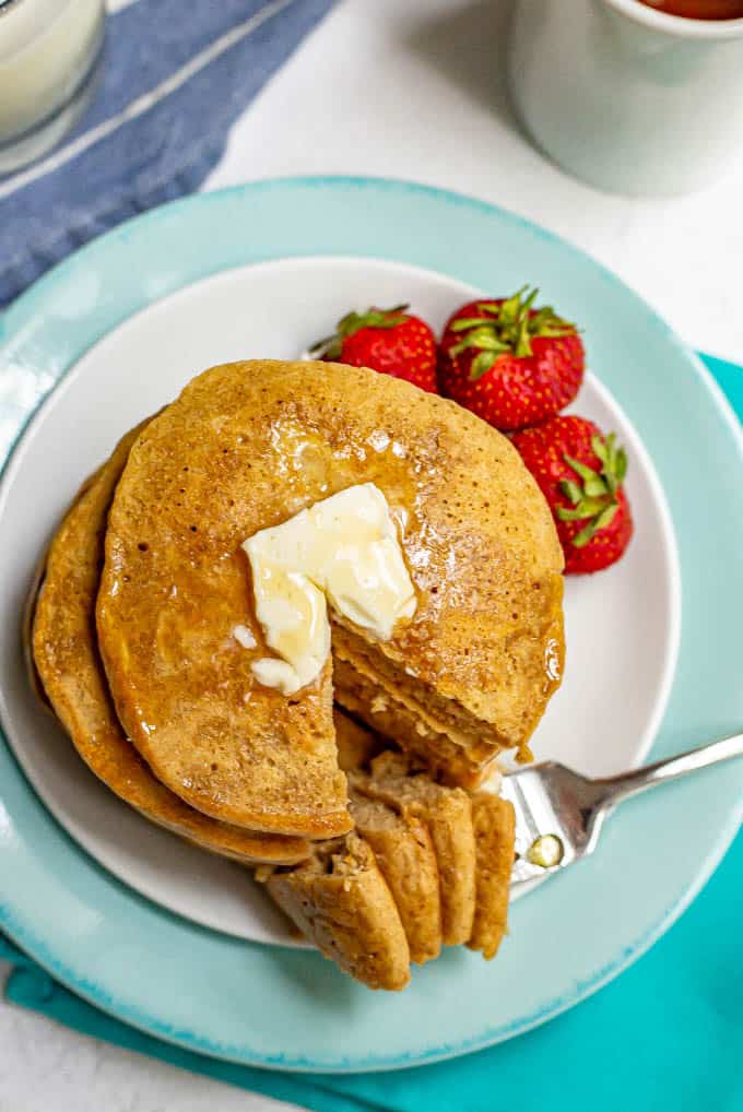 Stack of pancakes with a forkful taken out and laying on the side