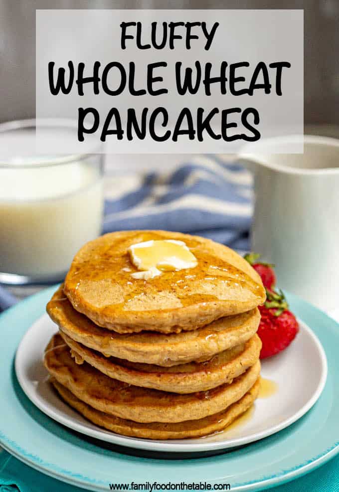 A stack of whole wheat pancakes on a white plate with butter and maple syrup on the top and a glass of milk in the background.