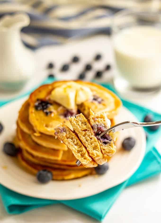 A forkful of blueberry pancakes being held up