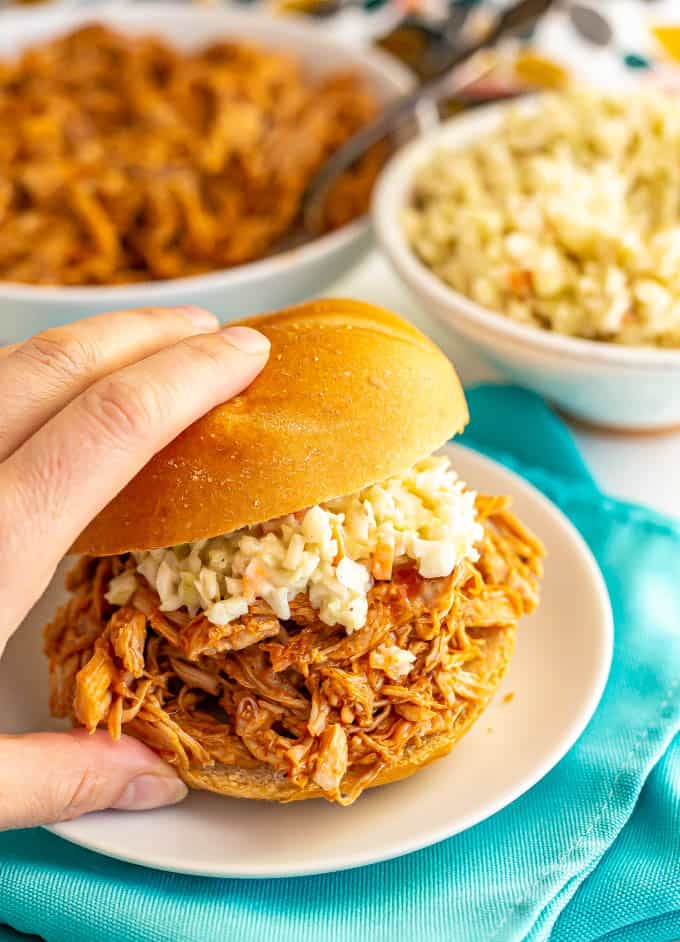 Hand picking up a BBQ pulled pork sandwich with coleslaw