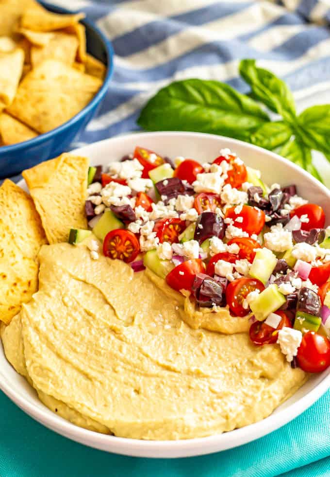 Hummus dip appetizer with chopped fresh veggies, feta cheese and pita chips for serving