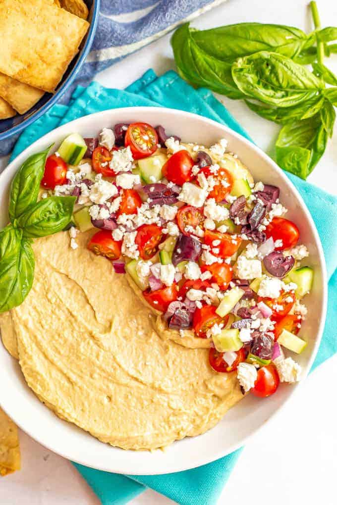 Hummus topped with chopped fresh veggies and served in a large white bowl