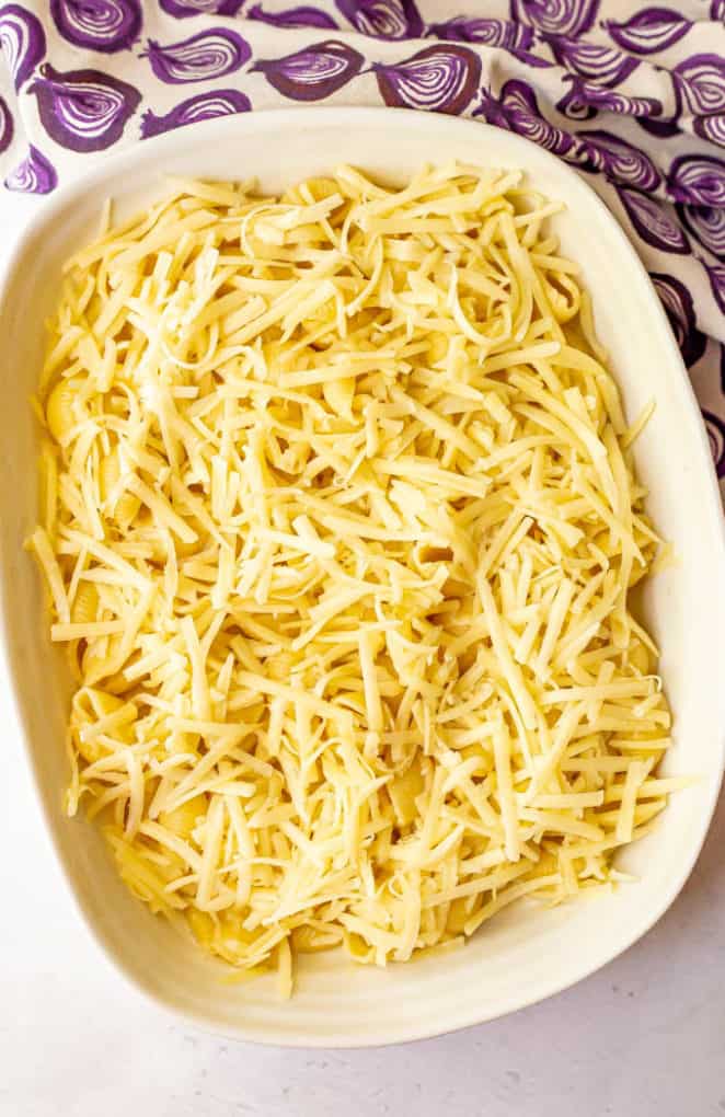 Mac and cheese with shredded cheese on top in a casserole dish before being baked