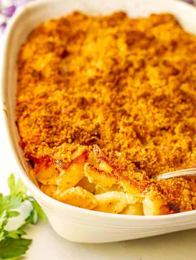 Classic baked mac and cheese has a crunchy, buttery breadcrumb crust and is comfort food at its best! Easy to make, with just 7 ingredients, this baked macaroni and cheese casserole is sure to satisfy! #macandcheese #pasta #pastarecipes #easyrecipe #holidaysides #Thanksgivingsides Baked macaroni and cheese casserole with a spoonful being taken out