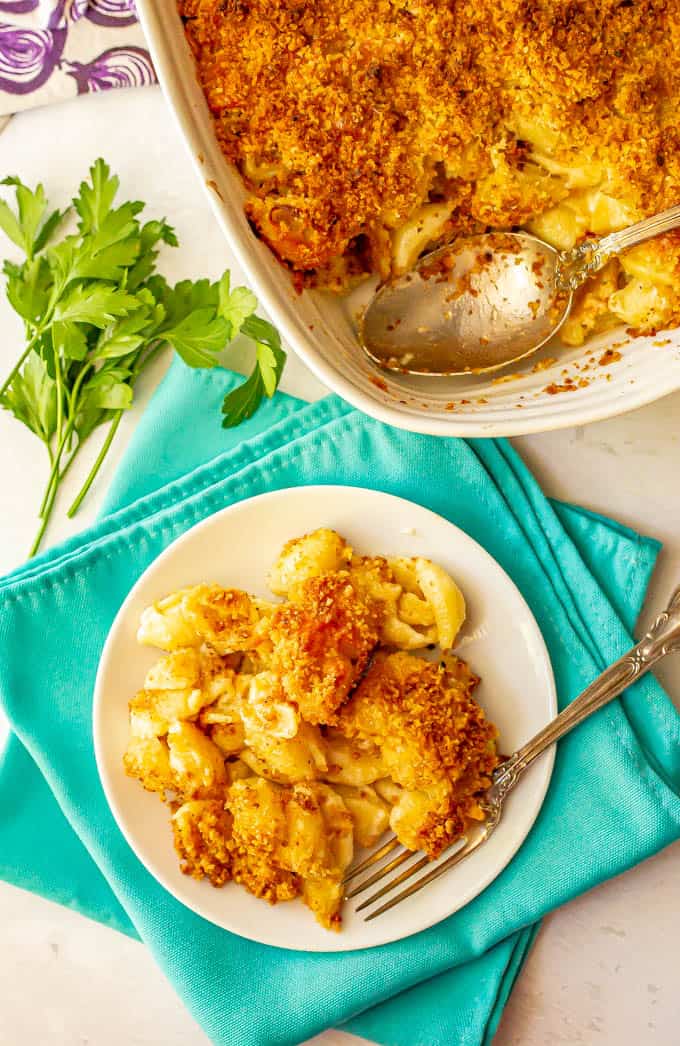 Crunchy baked mac and cheese served on a white plate with a fork and the casserole in the back