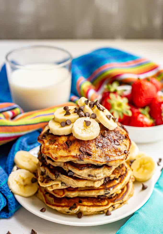 A stack of freshly made banana chocolate chip pancakes served with extra bananas and chocolate chips on top