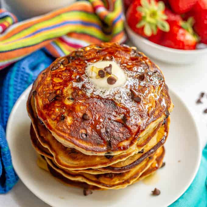 A stack of chocolate chip pancakes with butter and maple syrup on top