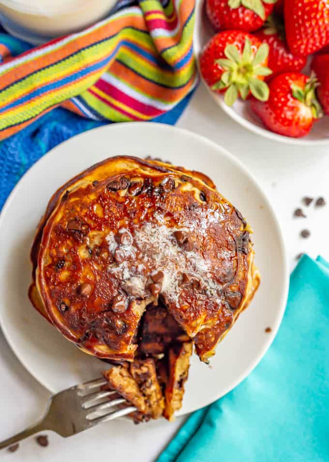 A forkful of chocolate chip pancakes taken out from a big stack