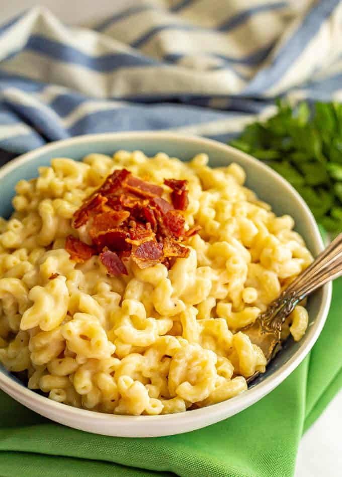 A bowlful of creamy macaroni and cheese with crumbled bacon on top