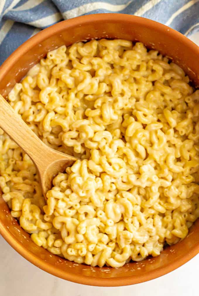 A spoonful of stovetop macaroni and cheese being scooped out of a pot