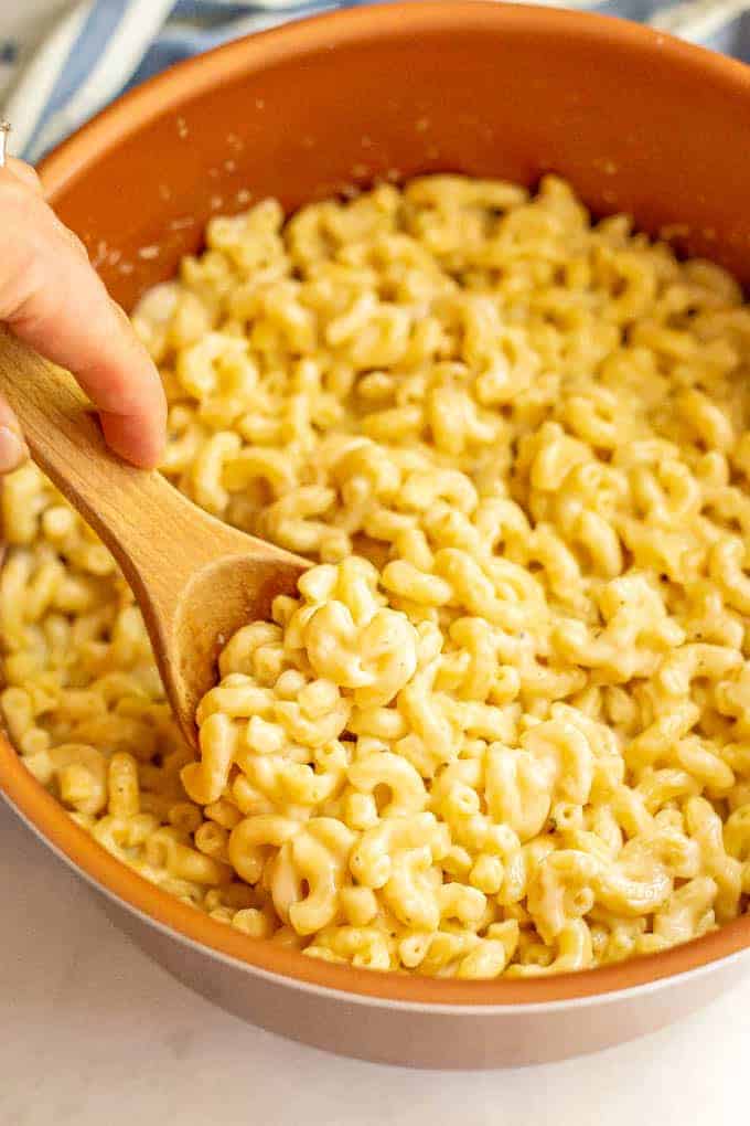 A spoonful of stovetop mac and cheese being scooped out of a pot