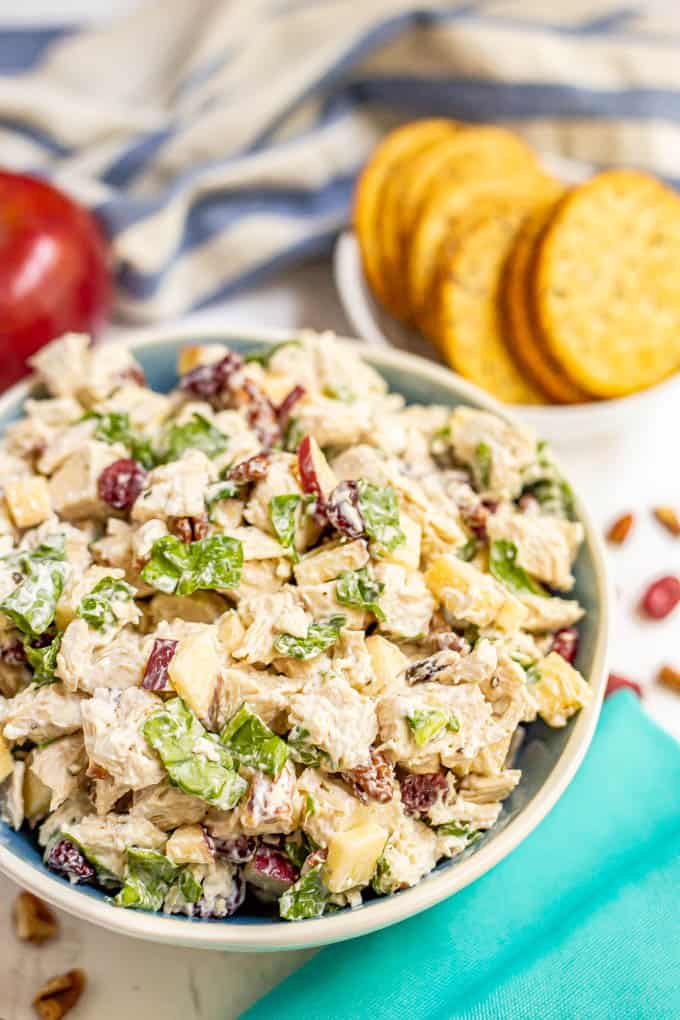 A serving bowl full of harvest chicken salad with dried cranberries and apples and spinach