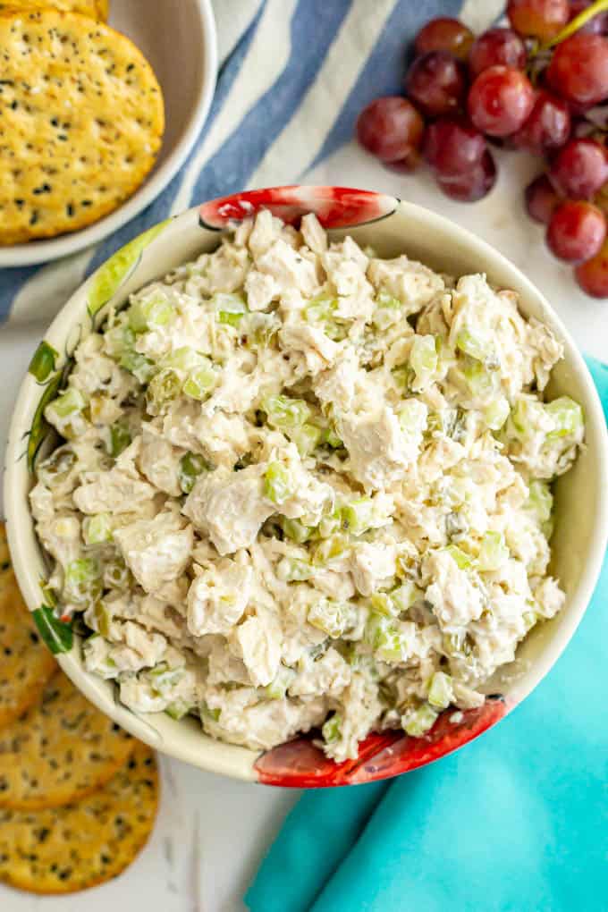 Healthy chicken salad in a large serving bowl with crackers and red grapes alongside